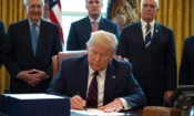 Президентът Доналд Тръмп подписва в Овалния кабинет на Белия дом на 27 март 2020 г. законодателния акт CARES, спасителен пакет от 2,2 трилиона долара за осигуряване на икономически облекчения по време на пандемията (Джим Уотсън / АФП чрез Getty Images)