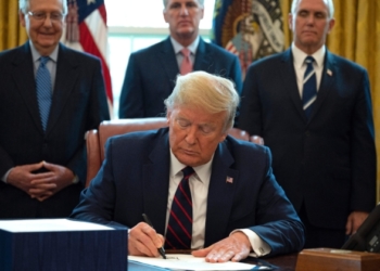 Президентът Доналд Тръмп подписва в Овалния кабинет на Белия дом на 27 март 2020 г. законодателния акт CARES, спасителен пакет от 2,2 трилиона долара за осигуряване на икономически облекчения по време на пандемията (Джим Уотсън / АФП чрез Getty Images)