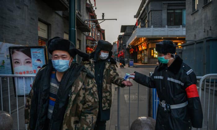 Китайската полиция мери температурата на граждани на временно поставен вход към търговски район в Пекин на 11 март 2020 г. (Кевин Фрейър/ Getty Images)