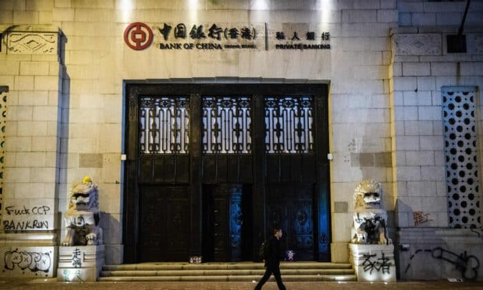 Мъж минава покрай графити, оставени от протестиращите на старата сграда на Банка на Китай след митинг за демокрация от Виктория Парк до Чатър Роуд в Хонконг на 8 декември 2019 г. (Антъни Уолъс /AFP via Getty Images)