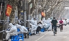 Служители, облечени в защитни дрехи, в близост до някои блокирани зони след откриването на нови случаи на COVID-19 в Шанхай на 14 март 2022 г. (Хектор Ретамал/AFP чрез Getty Images)
