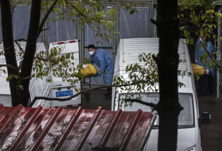 Погребални работници товарят тела във фургони за кремация в оживено местно погребално бюро в Шанхай на 13 януари 2023 г. (Kevin Frayer/Getty Images)