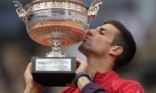 Снимка 1: Сръбският тенисист Новак Джокович целува трофея, докато празнува победата си във финалния мач на сингъл мъже на Откритото първенство на Франция по тенис на стадион Roland-Garros ("Ролан Гарос") в Париж на 11 юни 2023 г. (Christophe Ena/AP Photo)