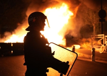 Пожарникар гледа как горят автомобили след размирици в Нантер, западно от Париж (Zakaria Abdelkafi/Getty Images)