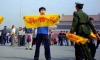 Китайски полицай се приближава до практикуващ Фалун Гонг на площад "Тиенанмън" в Пекин, докато той държи плакат с китайските йероглифи за "истинност, състрадание и търпение" - основните принципи на Фалун Гонг (С любезното съдействие на Minghui.org)