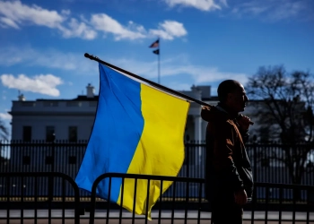 Мъж с украинско знаме стои на Пенсилвания авеню пред Белия дом (Samuel Corum/Getty Images)