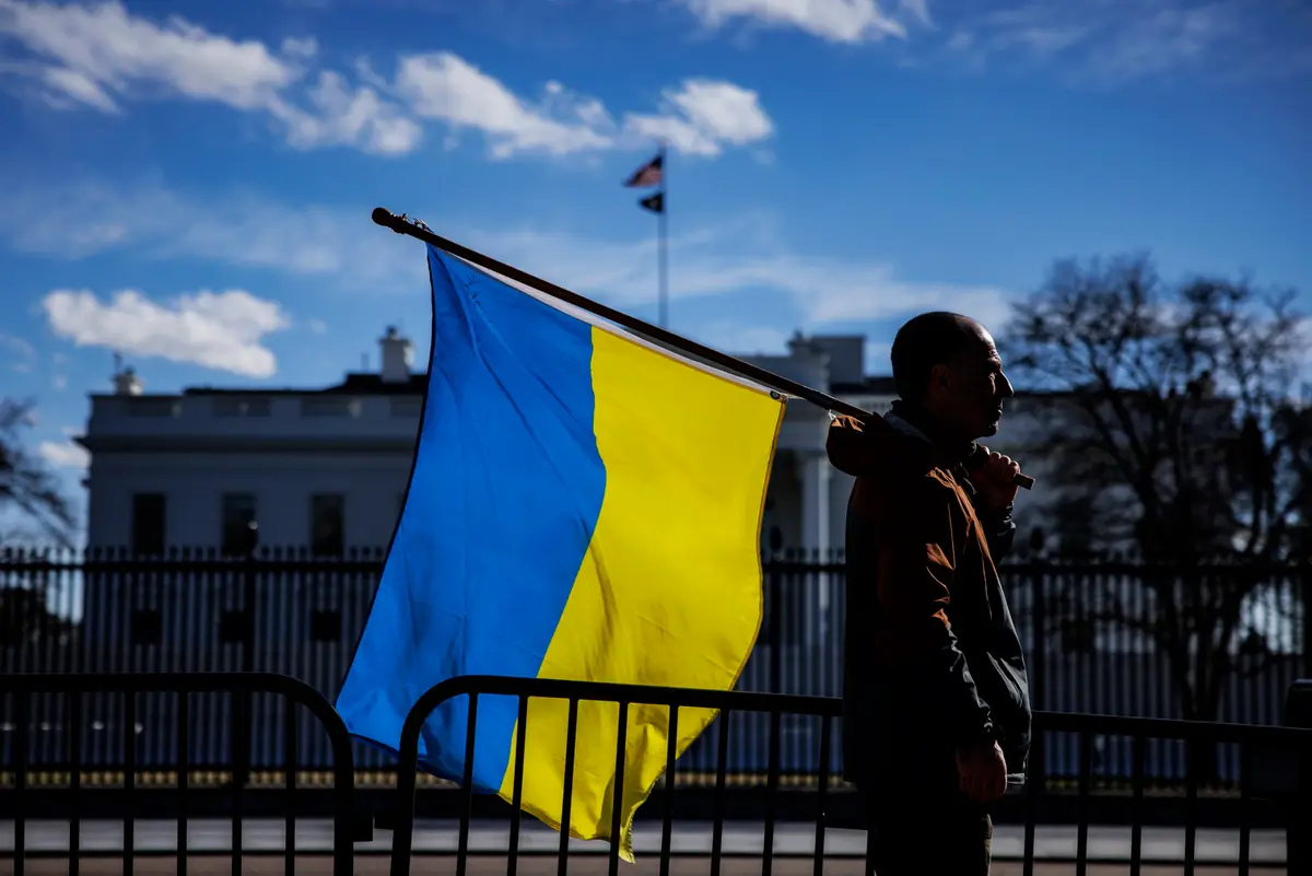 Мъж с украинско знаме стои на Пенсилвания авеню пред Белия дом (Samuel Corum/Getty Images)