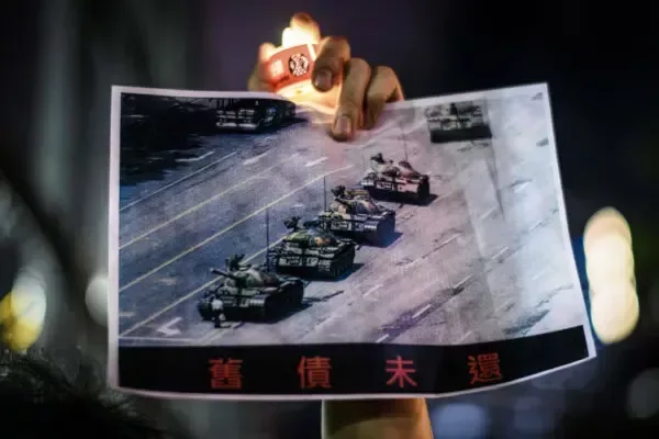 По време на възпоменателно шествие в памет на жертвите на клането на площад „Тиенанмън“ през 1989 г. в парк „Виктория“ в Хонконг мъж държи плакат на известния „Човекът пред танка“, 4 юни 2020 г. (Anthony Wallace/AFP via Getty Images)