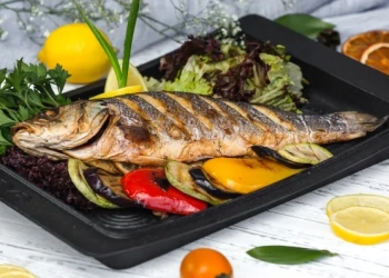 roasted fish garnished with lemon slices served with vegetables