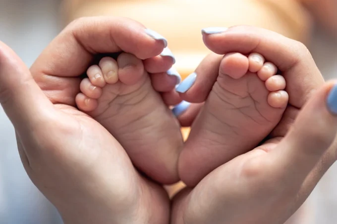 mom holds legs newborn baby her hands