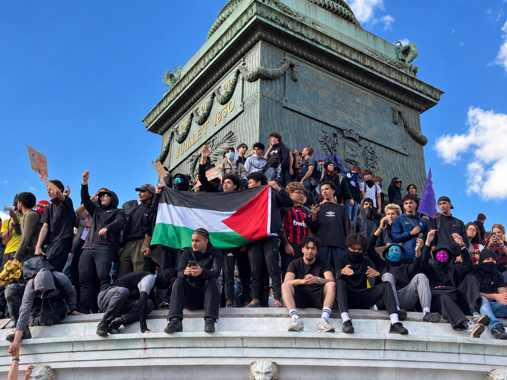 „Превзехме Бастилията“: Парижки ученици протестираха срещу полицията, а крайната левица се опитва да си припише движението 22 Протестиращи, някои от които с маски, се събират в подножието на Юлската колона на площад „Бастилия“ в Париж и държат палестинско знаме по време на гимназиален протест в Париж на 8 октомври 2026 г. (Etienne Fauchaire/The Epoch Times)