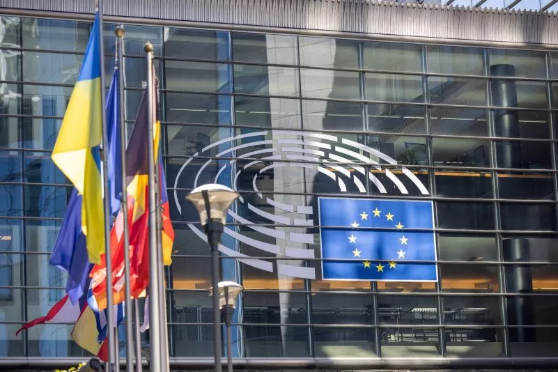 Знамена пред стъклената фасада на Европейския парламент с логото на парламента и флага на ЕС